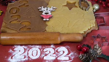 Dough for making homemade gingerbread cookies on a wooden board on a red background.Christmas and New Year 2022 concept. Selective focusの写真素材