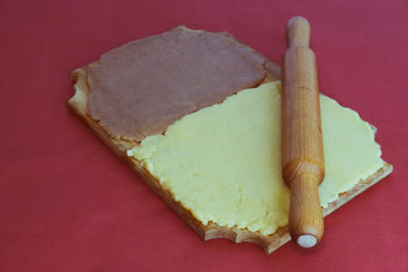 Dough for making homemade gingerbread cookies on a wooden board on a red backgroundの写真素材