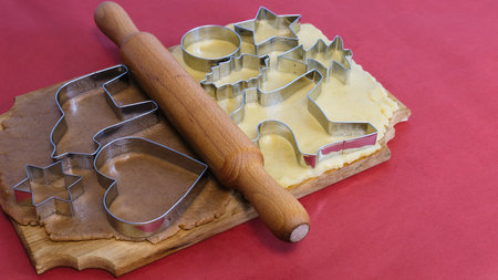 Dough for making homemade gingerbread cookies on a wooden board on a red background.Christmas and New Year 2022 concept. Selective focusの写真素材