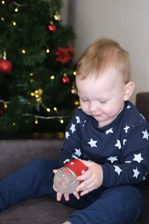 Beautiful little child on the background of a Christmas tree plays with a gift.Christmas and New Year conceptの写真素材