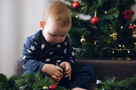 Beautiful little child on the background of a Christmas tree plays with a gift.Christmas and New Year conceptの写真素材