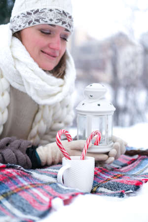 The girl lies on the snow in the winter forest or park. Concept - Christmas vacations and holidays.の写真素材