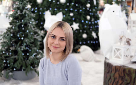 Portrait of a girl with blond hair on the background of a Christmas tree. Selective focusの写真素材