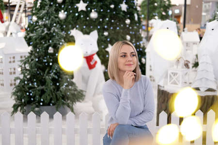 Portrait of a girl with blond hair on the background of a Christmas tree. Selective focusの写真素材