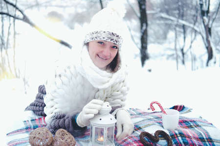 The girl lies on the snow in the winter forest or park. Concept - Christmas vacations and holidays