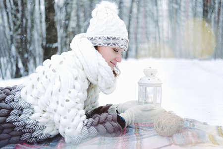 The girl lies on the snow in the winter forest or park. Concept - Christmas vacations and holidays