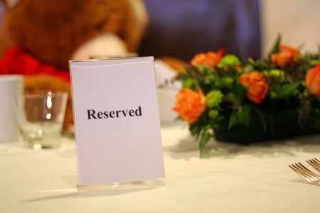 Reserved table at a fancy restaurant with at large teddy bear and roses.の写真素材
