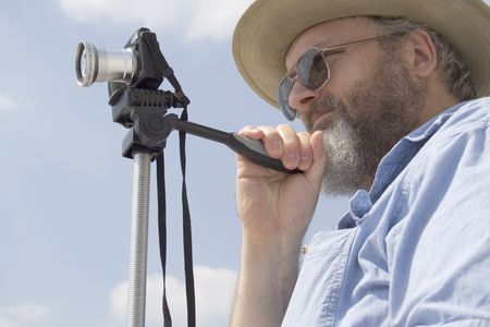 Photograph of a middle aged photographer with a compact camera on a tripod.