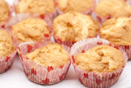 Fresh cupcake muffins in a heart decorated papers, ready to be frosted.の写真素材