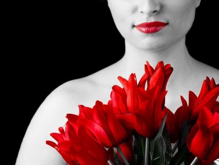 Black and white picture of young woman with red tulips. Only color left it's red.の写真素材