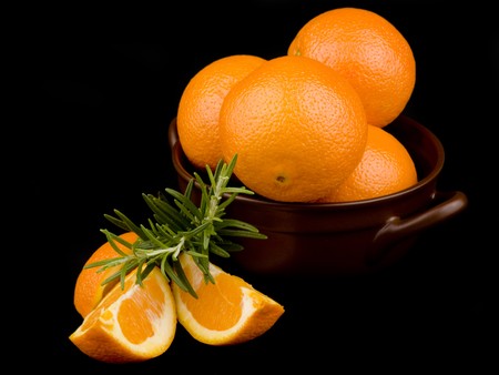 Oranges in ceramic bowl on black backgroundの写真素材