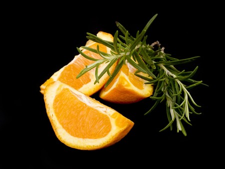 Three pieces of orange and fresh rosemary on black backgroundの写真素材