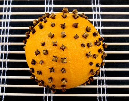 Aromatic orange with cloves on black bamboo mat backgroundの写真素材