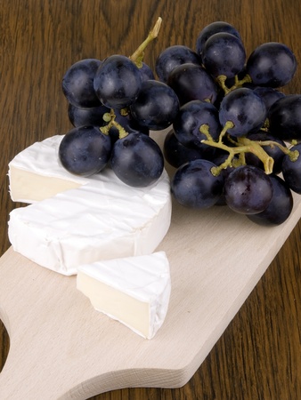 Camembert cheese with dark grapes on chopping boardの写真素材