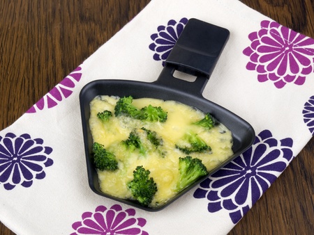 Raclette pan with cheese and broccoli on colorful napkinの写真素材
