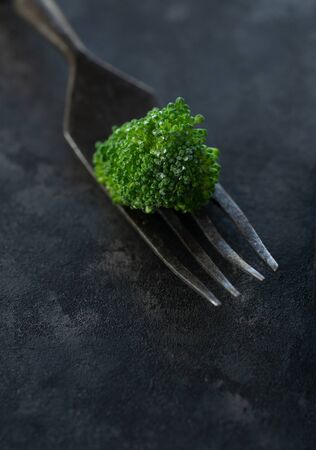 Close up broccoli with fork on black stone backgroundの写真素材