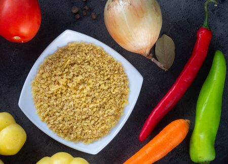 Dark table background of cooking. Grain and vegetables . Top view.