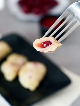 Homemade traditional Russian Ukrainian dumplings vareniki with sour cherry on a black plate vertical viewの写真素材