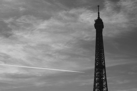 A plane draws a line behind the Eiffel Tower in Paris, Franceの写真素材