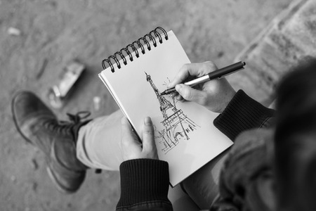 A girl makes a sketch of the Eiffel Tower in a notepadの写真素材