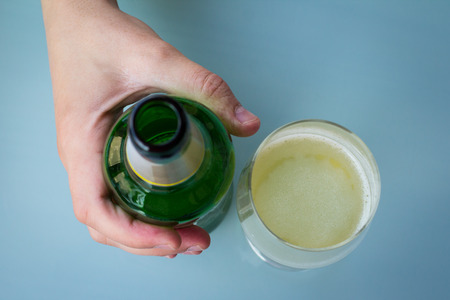 Hand holding a beer bottle close to a half filled beer glassの写真素材