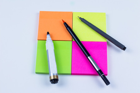 Square of colored sticky note with pens and markers on topの写真素材