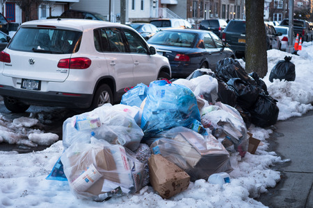 New York, USA - March 19th, 2017: Garbage bags stacked on a sidewalk in Queens, New York, USA.のeditorial素材