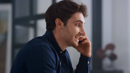 Closeup smiling man talking mobile phone in office. Close up of cheerful businessman having phone...