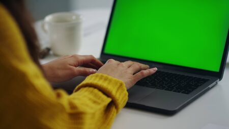 Closeup business woman hands working internet on laptop computer. Girl hands typing on green screen notebook in slow motion Close up female freelancer writing letter on notebook in office.の写真素材