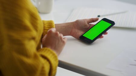 Closeup woman hands surfing internet on smartphone with chroma key in slow motion. Close up girl browsing cell phone with green screen. Business woman relaxing with mobile phone after work.の写真素材