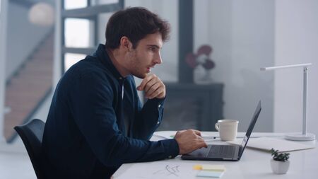 Happyr business man working on laptop computer in office. Positive man getting good news on email. Excited businessman winning project. Cheerful winner enjoy success at home officeの写真素材