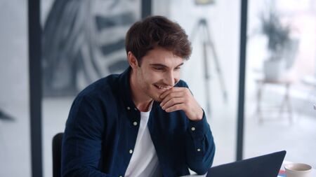 Portrait of male professional looking documents on notebook in slow motion. Happy man analyzing financial charts on computer in office. Close up smiling businessman working on laptop computer.の写真素材