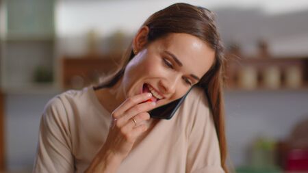 Smiling woman talking phone at home in slow motion. Housewife cutting vegetables for salad on...