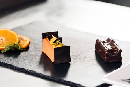 Cake at professional kitchen. Orange cake with chocolate at kitchen table. Closeup orange dessert with orange slices at restaurant kitchen.の写真素材