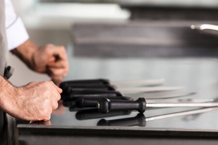Chef hands with knives at kitchen restaurant. Closeup chef hands with knives on workplace. Male in...