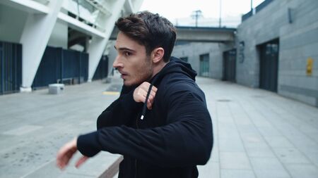 Serious man practicing box in city street. Portrait of focused man making box gestures near stadium. Closeup handsome man boxing outside in slow motion.の写真素材