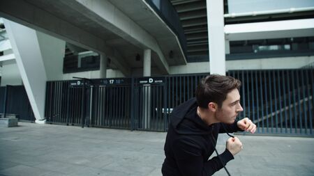 Closeup boxer man training punch on urban street. Portrait of male fighter boxing outdoor. Young guy...