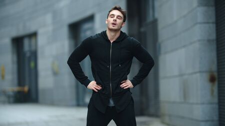 Fit man warming up outdoor in slow motion. Sporty man stretching neck on street training. Male athlete having fitness workout on urban street.の写真素材