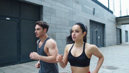 Closeup sporty couple starting run outdoor. Athlete man and woman training run exercise on urban...