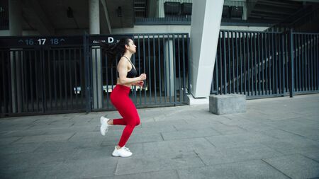 Fitness girl running outdoor in slow motion. Athlete woman training run exercise at street workout....