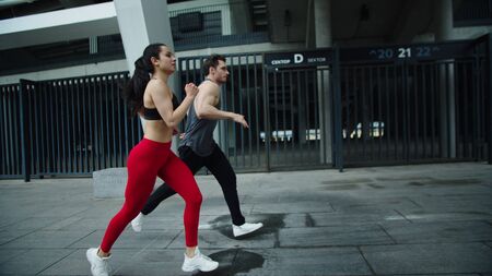 Sport couple jogging at cardio training outdoor. Fitness man and woman running together at morning...