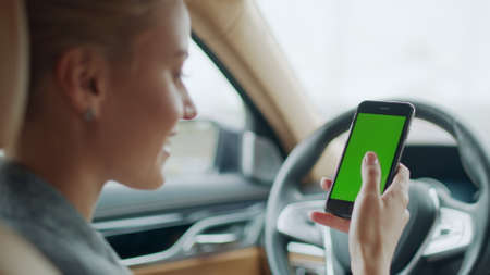 Portrait smiling business woman holding phone in hand behind steering wheel. Cheerful businesswoman...