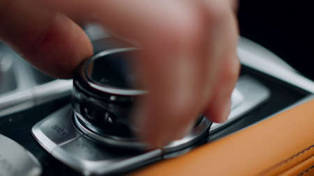 Close up unrecognizable person using control knob at modern car. Closeup man hand touching knob on...