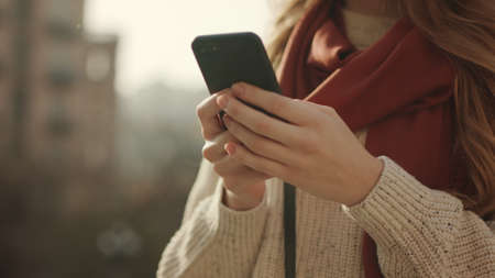 Close up woman hands messaging by mobile phone outdoors. Unrecognizable female person touching...