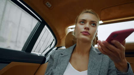 Thinking businesswoman calling mobile phone at automobile. Portrait thoughtful female entrepreneur...