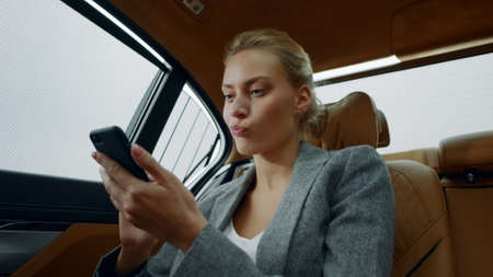 Portrait of young business woman reading bad news in smartphone. Tired businesswoman typing letter...