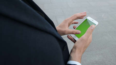 Overhead view businessman hands using cellphone on urban street. Male worker scrolling smartphone...