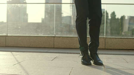 Close up unrecognizable businessman feet dancing on city street in slow motion. Male professional...