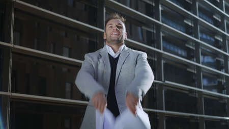 Happy businessman throwing documents on city street. Smiling male manager celebrating success...