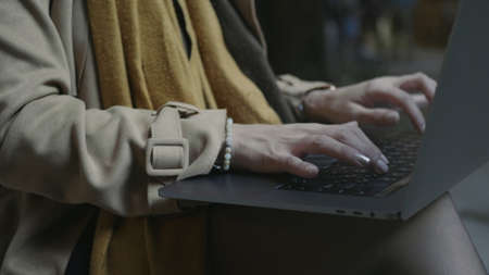 Unrecognizable female student using touchpad on laptop computer outdoors. Closeup girl hands working on computer in slow motion. Business woman hands typing on laptop outsideの写真素材